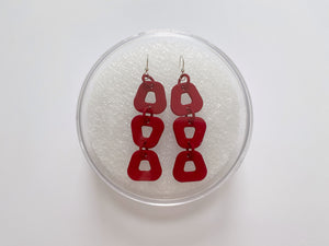Trapezoid hook earrings in their case, made from red 3D printed nylon with sterling silver components
